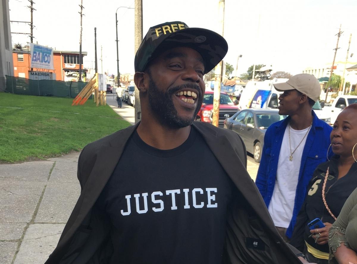 Black male smiles at bystanders as he shows his t-shirt with the word "Justice" on it.