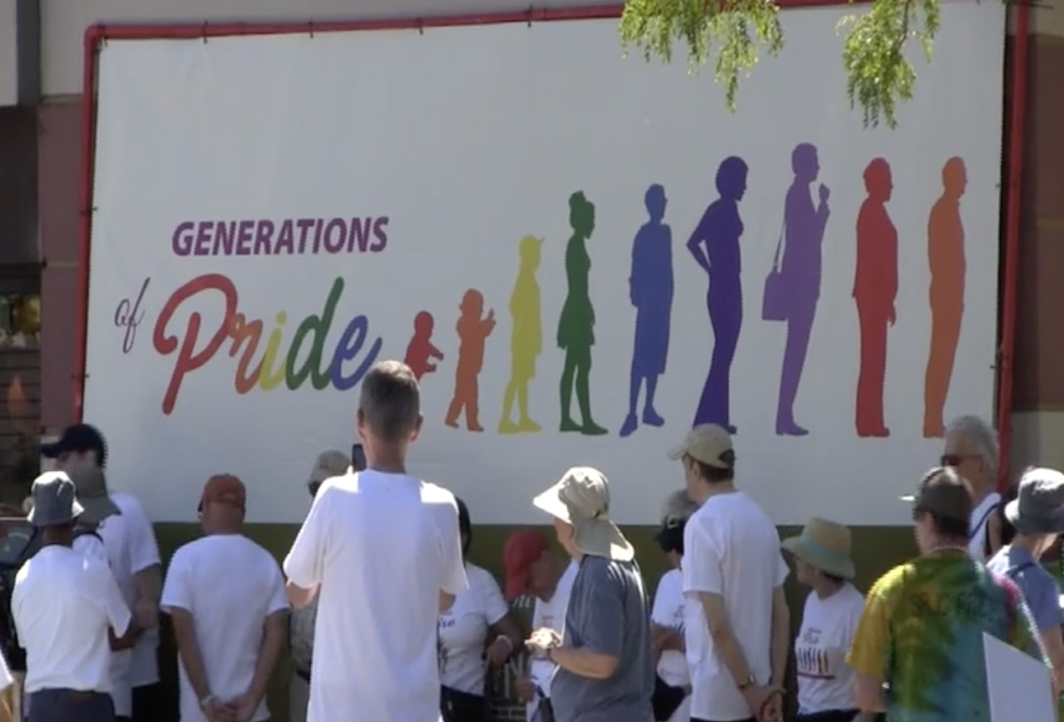 retirees stand before a rainbow colored poster reading "generations of pride."