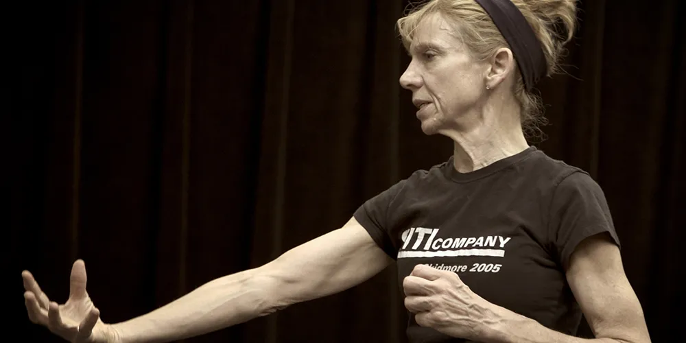 Anne Bogart is acting while wearing black clothes.