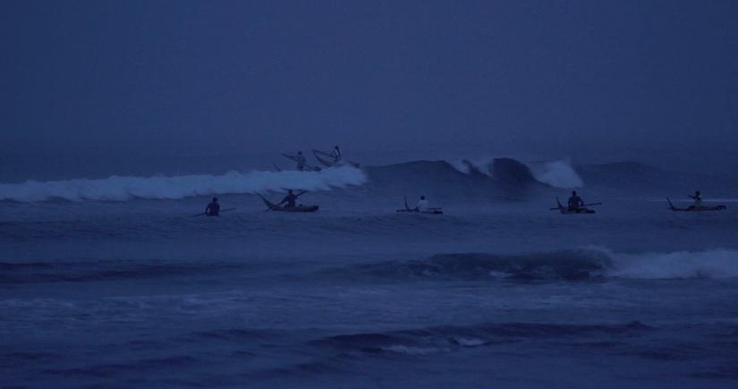 A group of Peruvian fishermen going into the ocean at dawn.