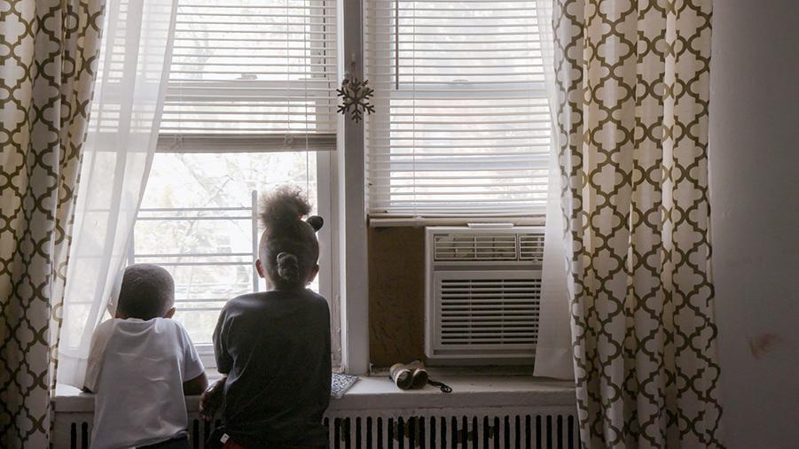 A boy and a girl is looking out at a window.