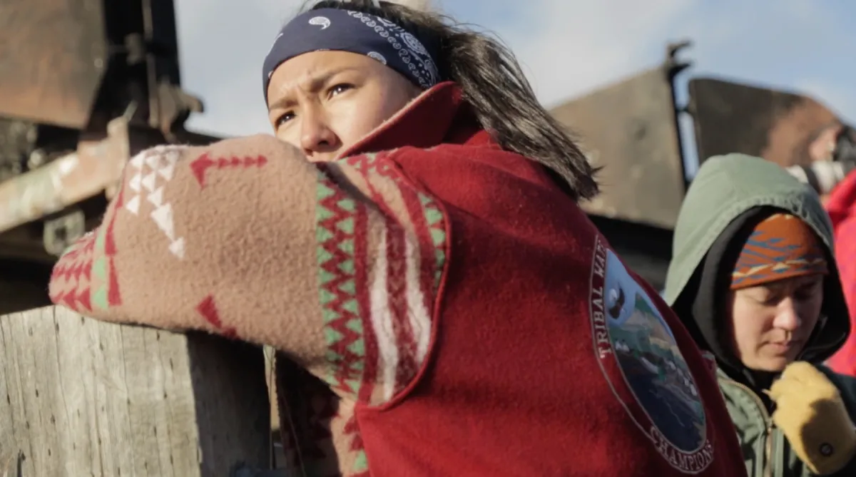 A Native American woman leaned over a fence