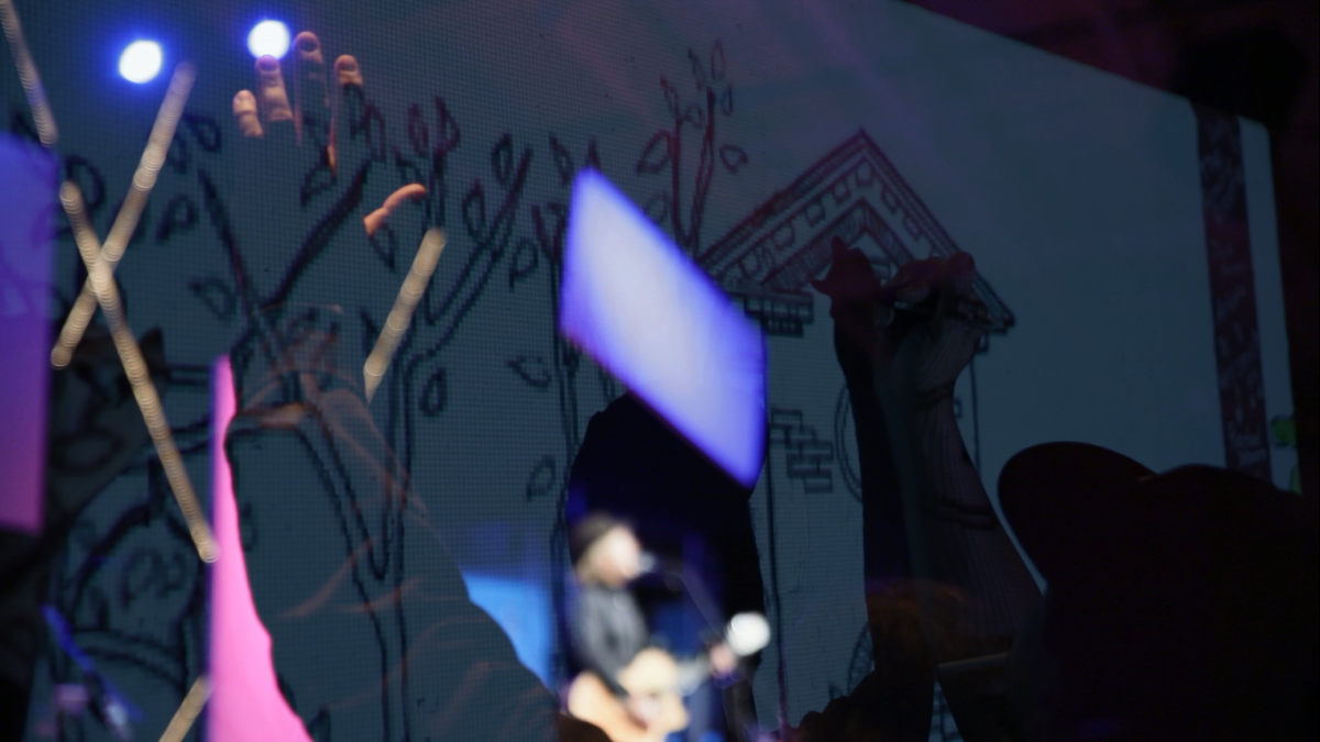 abstract superimposed image of fans raising their hands and a man playing guitar on stage.
