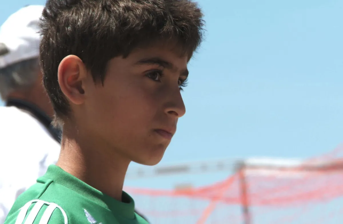 Mark Kabban watches a soccer game next to his coach.
