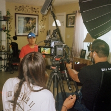 Behind-the-scenes photo inside a house. Pedro sits in front of the camera with Set holding a boom microphone next to cinematographer Richard Hama.