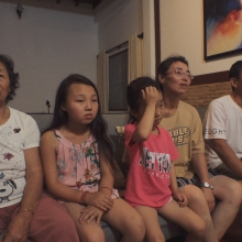Still image from 'Beyond Utopia,' showing five members of a North Korean family sitting on a couch.