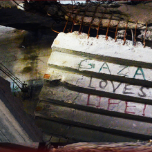 A concrete slab inside a collapsed building with "Gaza Loves Life!" painted on it