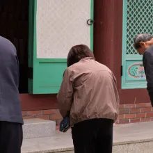 Three individuals wearing jackets bowing with their backs to the camera