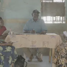 Photo of Rhoda and the Luo council of elders in a pre-mediation meeting