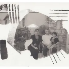 Image for 'My Father and Qaddafi.' Two adults and a child sit together in front of a bush and wall, posing for a picture.