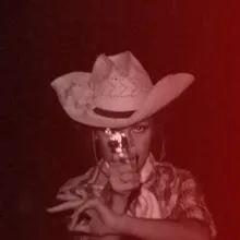 A red-tinted image of a young boy pointing a gun at the camera.