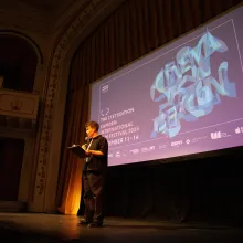 On a large stage with a Camden International Film Festival slide, a short-haired woman speaks into a microphone.