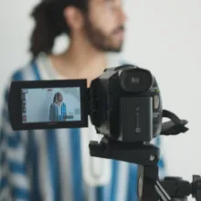 A man turns away from the camera, against a white wall.