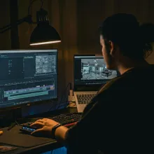 Man sits at his work computer setup where he's seen using video editing software
