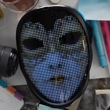 A picture of several items on a table including; A mask that one mom wears in the film, a camera, pens, sticky notes, and several other small items.