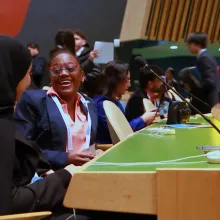 Two international high school delegates share a candid moment of laughter inside the United Nations General Assembly Hall during the WFUNA International Model United Nations conference. Surrounded by the iconic setting of global diplomacy, the image captures the intersection of youth, leadership, friendship, and cross-cultural connection that defines The Delegates.