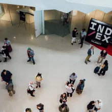Bird's eye view of a gathering of folks with a step-and-repeat branded as IND/EX seen in the background