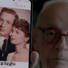 Man shows us a photo of two young lovers on his phone.
