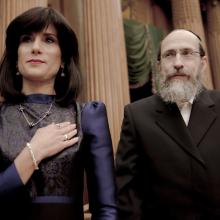 A jewish couple, the wife is being sworn in as the judge inside a courthouse