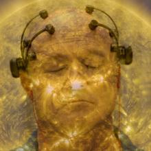 A man, who is particiapting in a neuroscience focus group, has his eyes closed, and is wearing a device on his head comprised of four neurosensors attached to the top of his head and twolarger sensors above each ear. He in enveloped in a golden aura that resembles the sun.