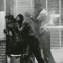 Black and white film still from 'Mighty Time Volume 2: The Children's March' of three Black people being hit with a high-pressure hose on the sidewalk. Courtesy of Tell the Truth Pictures