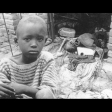 A child looks sadly; there's a corpse in the background. From Daniele Lacourse and Yvan Patry's 'Chronicle of a Genocide Foretold.' (Canada, 164 min., 1996)