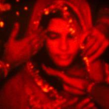 A red filtered image of a Hindu South Asian bride. She is wearing a veil. From Payal Kapadia’s ‘A Night of Knowing Nothing.’ Courtesy of TIFF