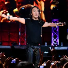 Filipino-American musician Arnel Pineda performing in a concert. He is wearing a black shirt and leather pants. Image from Ramona Diaz’s ‘Don't Stop Believin': Everyman's Journey.’ Courtesy of Amazon Prime.