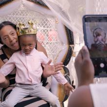 Shanona is a middle-aged Black woman, seen here holding her son, a Black boy wearing a gold toy crown. From Loira Limbal’s ‘Through the Night.’ Photo by Naiti Gámez. Courtesy of POV.