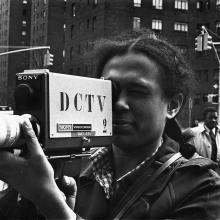 A black-and-white image of a woman with dark skin and dark curly hair holding an early Sony video camera. Courtesy of DCTV