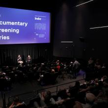 Two people sit in front of an audience. The projection behind them reads "ida documentary screening series." From a 2019 IDA Screening Series conversation with 'The Amazing Johnathan Documentary' team.