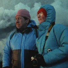 Volcanologists Katia and Maurice Krafft are a white couple seen here wearing blue jackets, against volcanoes emitting smoke. From Sara Dosa’s ‘Fire of Love.’ Courtesy of Sundance Institute.