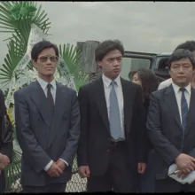 Four Chinese dissidents--one woman and three men--dressed in suits, stand in New York City's Battery Park. From 1989 footage from the suspended project 'Tiananmen/China Today.' Courtesy of Christine Choy 