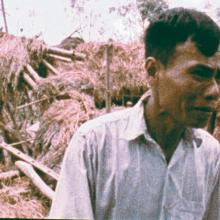 A middle-aged Vietnamese man looks in despair in front of damaged home