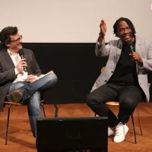 Ben Mankiewicz is a white male TV personality in conversation with Roger Ross Williams, a Black male filmmaker during IDA's Conversation Series, in 2016. Image courtesy of Conversa. 