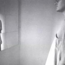 A man looks at a distorted reflection of himself in the mirror. 