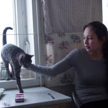 Kirsten Kleist Petersen is a young woman wearing a gray shirt. She is sitting on a chair by a window and petting her cat. From Sidse Torstholm Larsen and Sturla Pilskog’s ‘Winter’s Yearning.’ Courtesy of 'POV.' 