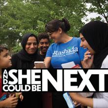 Congresswoman Rashida Tlaib in a blue tshirt on her campaign, surrounded by a family of Muslim supporters