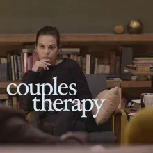 Two adult is out of focused in the foreground facing an adult female therapist