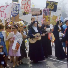 A group of people protesting, including several nuns in black robes.
