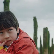 A young boy in an orange coat looking to the side
