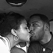 Old picture of a Black couple in the car, giving each other a kiss