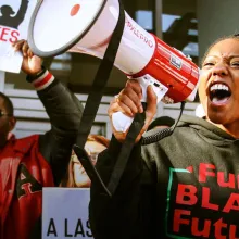 Young Black adults are at a rally, speaking to the megaphone