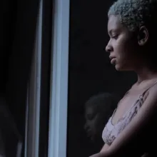 An African-American female looking at herself through the mirror.