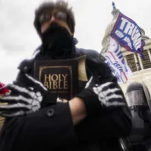 January 6, 2021. A ghoulish figure clasps a Bible amidst the crowd of insurrectionists on the Eastern Front of the U.S. Capitol.