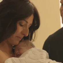 Mother swaddles her newborn who was conceived through surrogacy. 