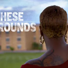 A student looks at her high school building from a distance, title treatment reads ON THESE GROUNDS.