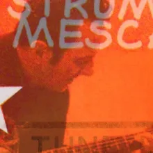 A White man dressed in black leans over a guitar and strums. 