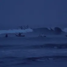A group of Peruvian fishermen going into the ocean at dawn.