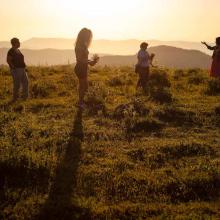 Four women from Artsakh gather flowers on a mountaintop at sunrise.